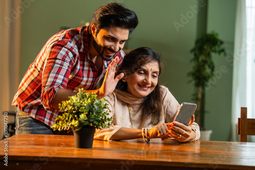 Canvas Print Elderly Indian mother and son viewing photos or video calling on a smartphone in