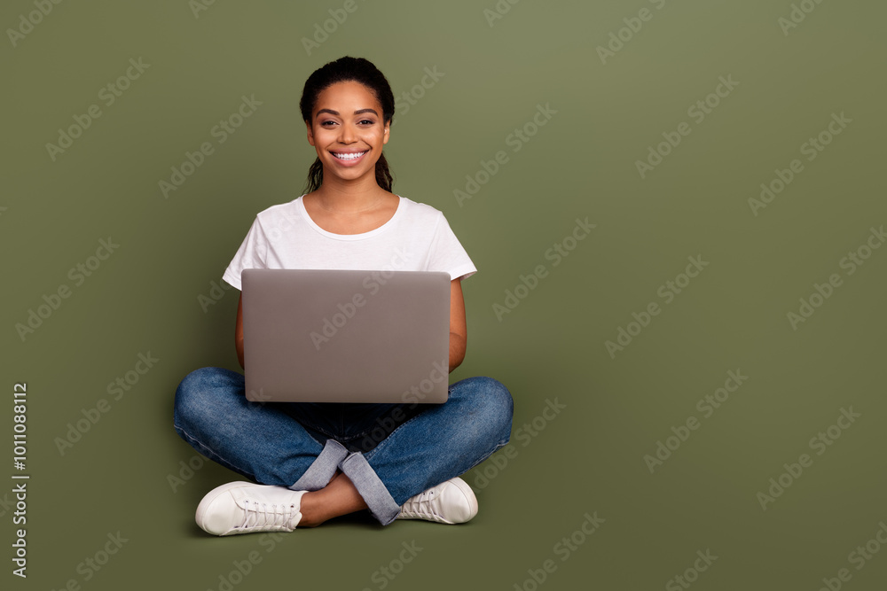Photo portrait of cheerful young girl working sitting floor with laptop alone learning something isolated on khaki color background Photo portrait of cheerful young girl working sitting floor with laptop alone learning something isolated on khaki color background
