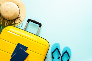 Suitcase, hat and flip flops on blue background. Happy Holidays, travel concept. Flat lay with space for text.