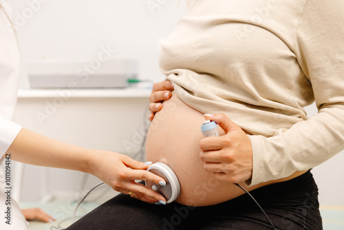 Foto Doctor prepares a pregnant woman for checking fetal heartbeat by fetal monitoring