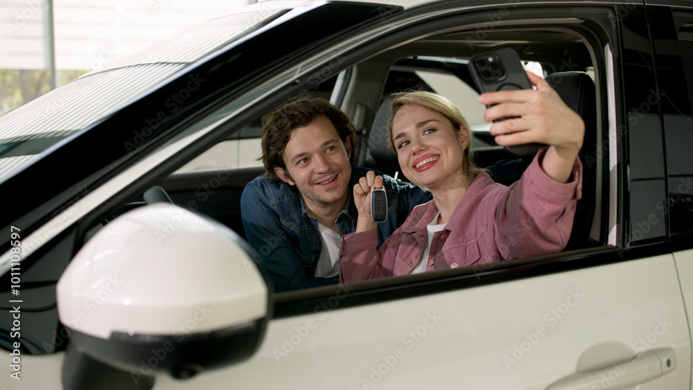 A happy married couple takes a selfie on a phone in a brand new purchased car. The concept of positive emotions and a long-awaited purchase. A happy married couple takes a selfie on a phone in a brand new purchased car. The concept of positive emotions and a long-awaited purchase.