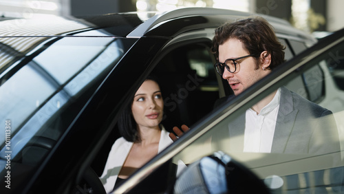 A confident car dealer discusses discounts and benefits of a new car with the buyer. This exchange highlights the excitement of buying and test-driving a new car.