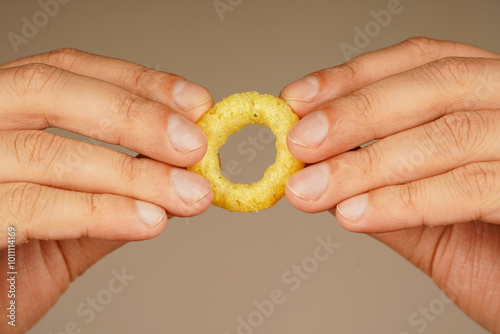 Snack for beer. Fast food. Junk food. Cooked tasty appetizer meal. Fried rings. Corn onion rings. Unhealthy food. Onion ring. Deep fried onion rings. Eating onion rings. Man holds onion ring.