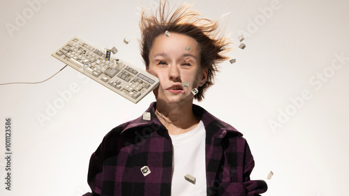 Keyboard smacks woman's face, scattering keys flying around in mid-air in motion against white studio background. Work life. Concept of social media, business, negative emotions. photo