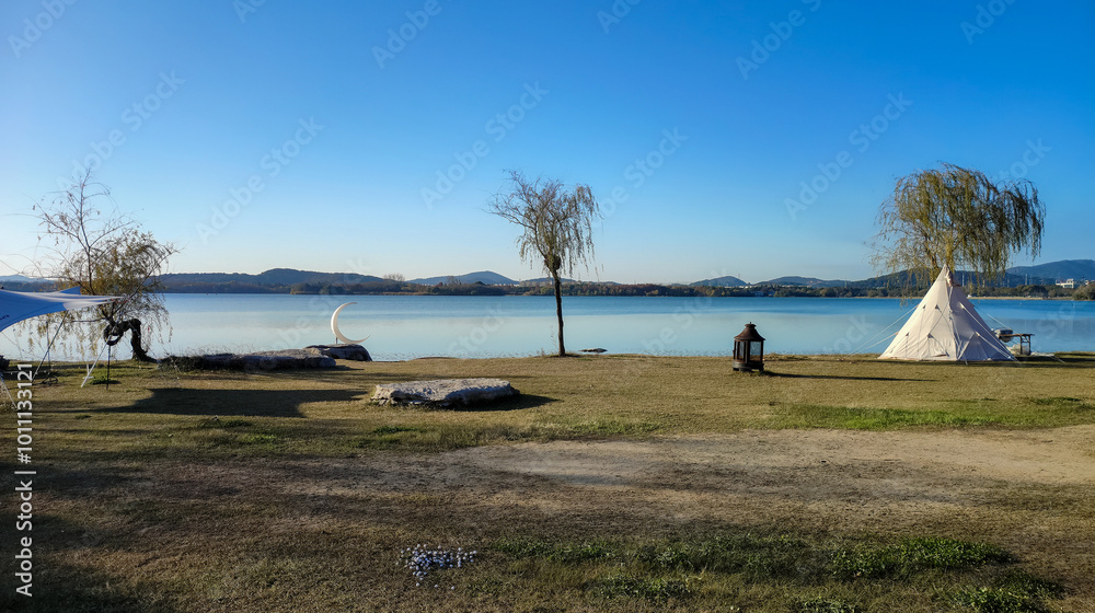 Obraz premium Tranquil Lakeside Scene with Tipi and Solitary Figure