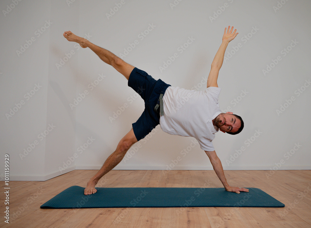 Naklejka premium Caucasian Latino male practicing opening and balancing yoga posture during home session