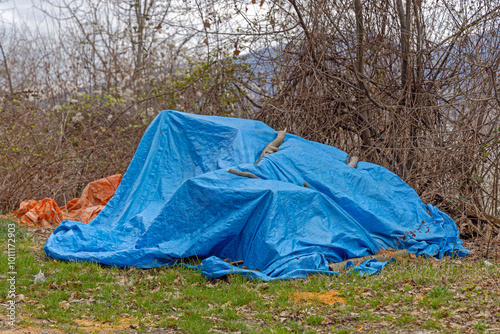 Big Pile of Stuff Hidden Under Blue Tarp Cover in Yard Garden