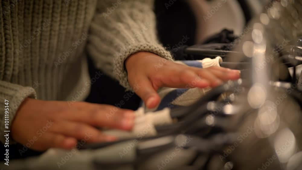 A CloseUp View of Hand Organizing Various Clothing Items on Hangers Within a Retail Store A CloseUp View of Hand Organizing Various Clothing Items on Hangers Within a Retail Store