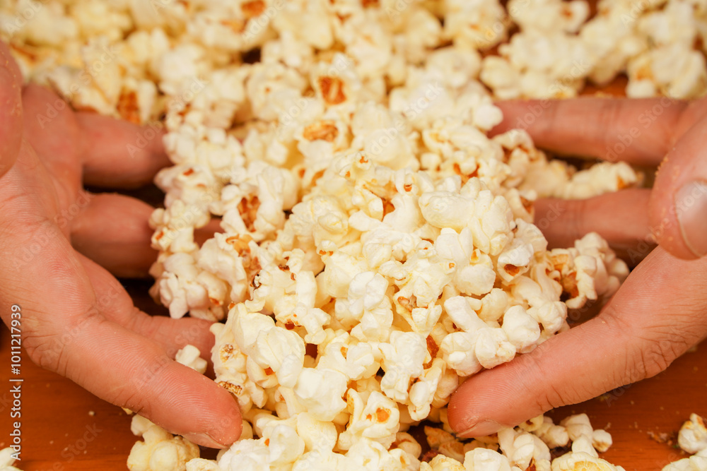 Flavored spicy popcorn in man's hands. Salted popcorn. Popcorn. Fast food. Junk food. Snack for cinema. Popcorn scattered on table surface. Delicious snack to eat in the cinema. Flavored spicy popcorn in man's hands. Salted popcorn. Popcorn. Fast food. Junk food. Snack for cinema. Popcorn scattered on table surface. Delicious snack to eat in the cinema.