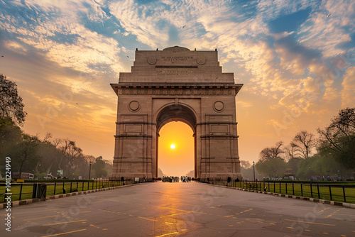 Majestic view of India Gate under a clear blue sky, symbolizing Delhi’s rich heritage and history. The iconic sandstone arch stands tall, surrounded by lush greenery and tourists.