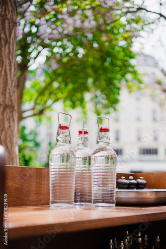 Three Clear Flip-Flop Bottles of Water Standing on a Wooden Table in the Sun