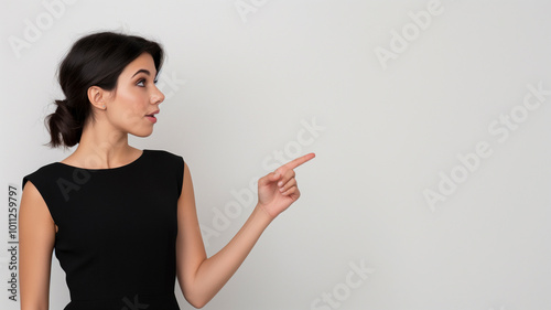 Obraz na płótnie Beautiful girl posing on white background and pointing finger at place for advertisement and text w salonie