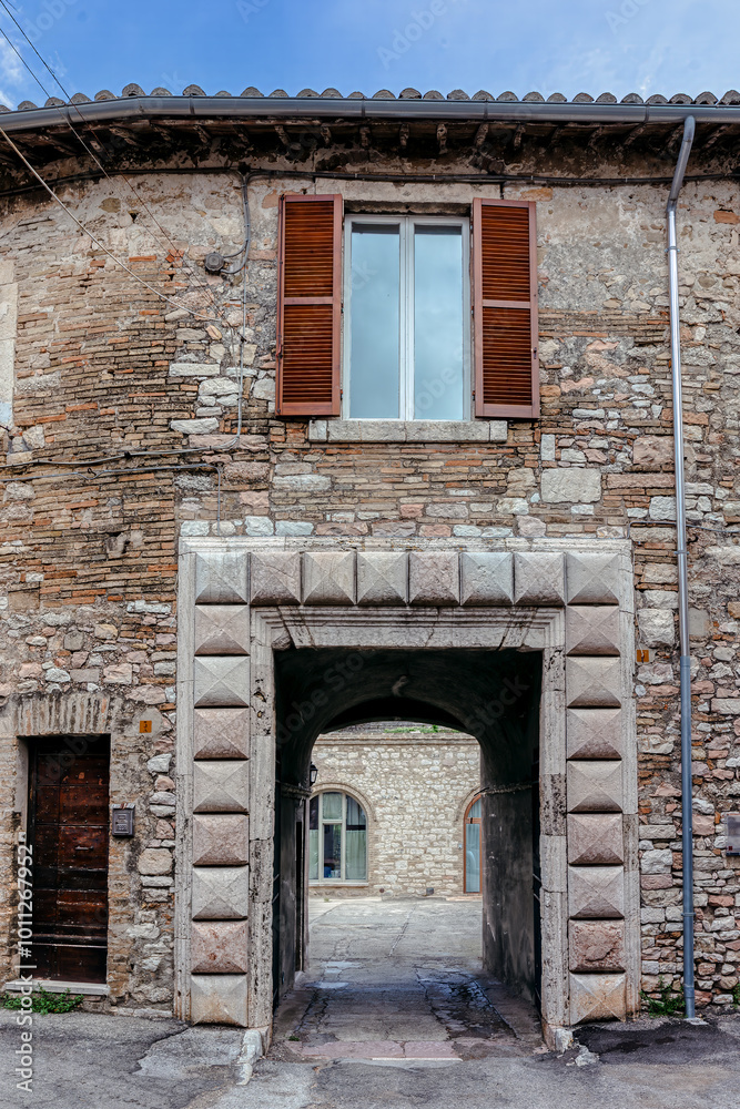 A charming cobblestone street in medieval Assisi, (Umbria, Italy), featuring ancient stone buildings and vibrant flower pots A charming cobblestone street in medieval Assisi, (Umbria, Italy), featuring ancient stone buildings and vibrant flower pots
