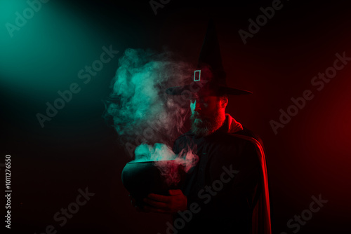 Photo of sorcerer hold cauldron halloween event make magic ritual isolated on dark misty mysterious background photo