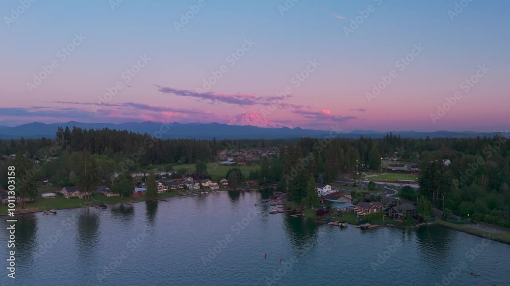 Drone shot rising over Bonney Lake in Washington Sate to reveal a pink glowing mountain in the distance. Drone shot rising over Bonney Lake in Washington Sate to reveal a pink glowing mountain in the distance.