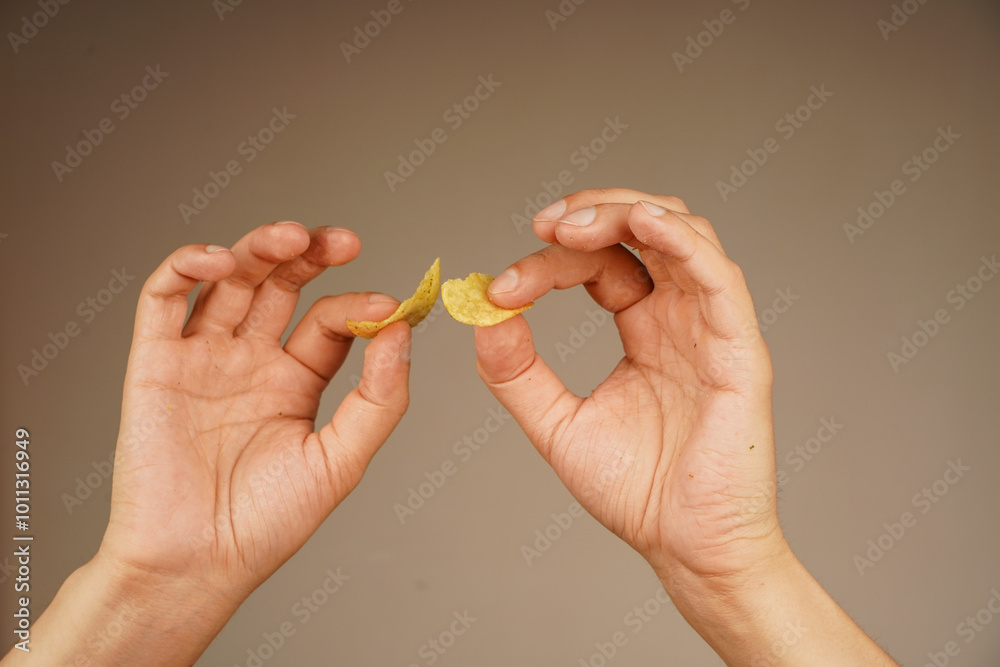 Hands hold potato chip. Calories. Obesity. American food. Unhealthy lifestyle. Man eating potato chips. Fast food. Junk food. Hands hold potato chip. Calories. Obesity. American food. Unhealthy lifestyle. Man eating potato chips. Fast food. Junk food.