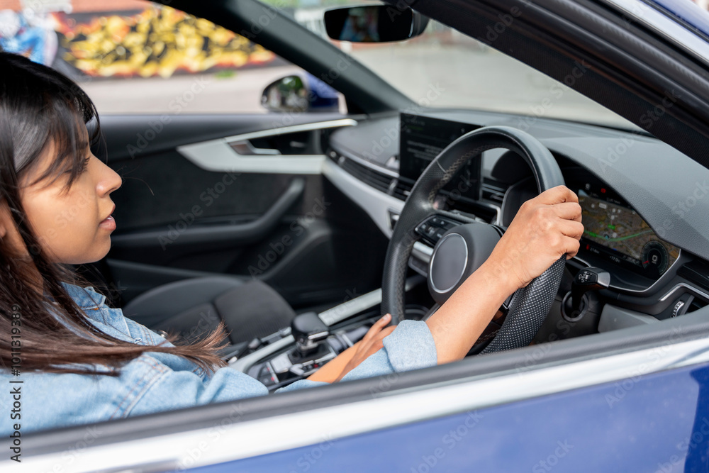 A young woman enjoying her time behind the wheel of a stylish car on a bright day in the city A young woman enjoying her time behind the wheel of a stylish car on a bright day in the city