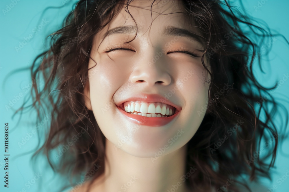 Joyful woman with curly hair smiling brightly against a vibrant blue background. Joyful woman with curly hair smiling brightly against a vibrant blue background.