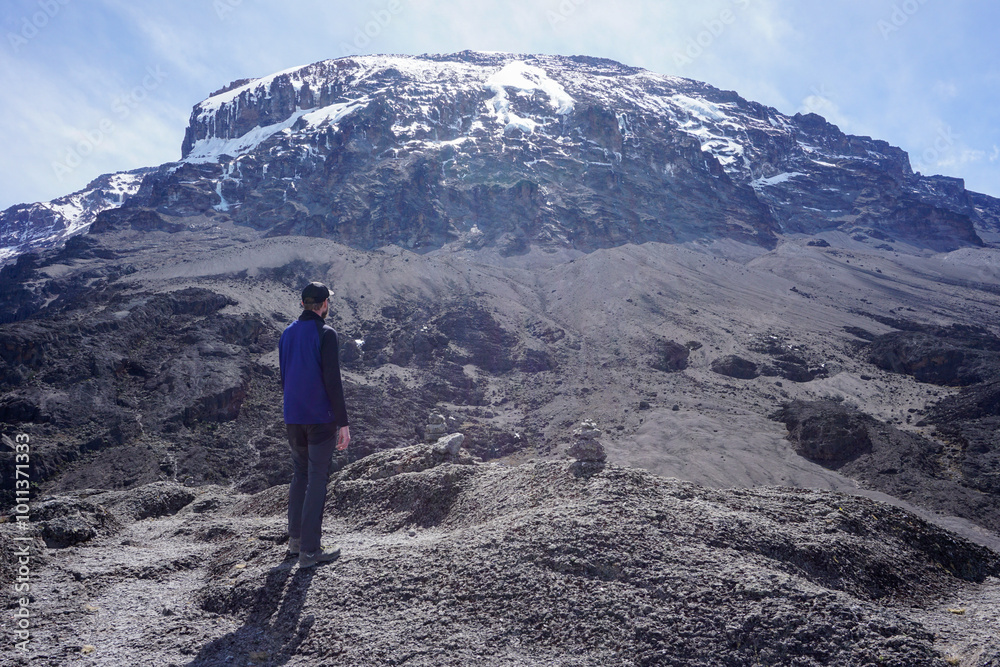 European hiker in front of snowy summit Mount Kilimanjaro - achieve your goals - dreamer - motivation - rocky terrain