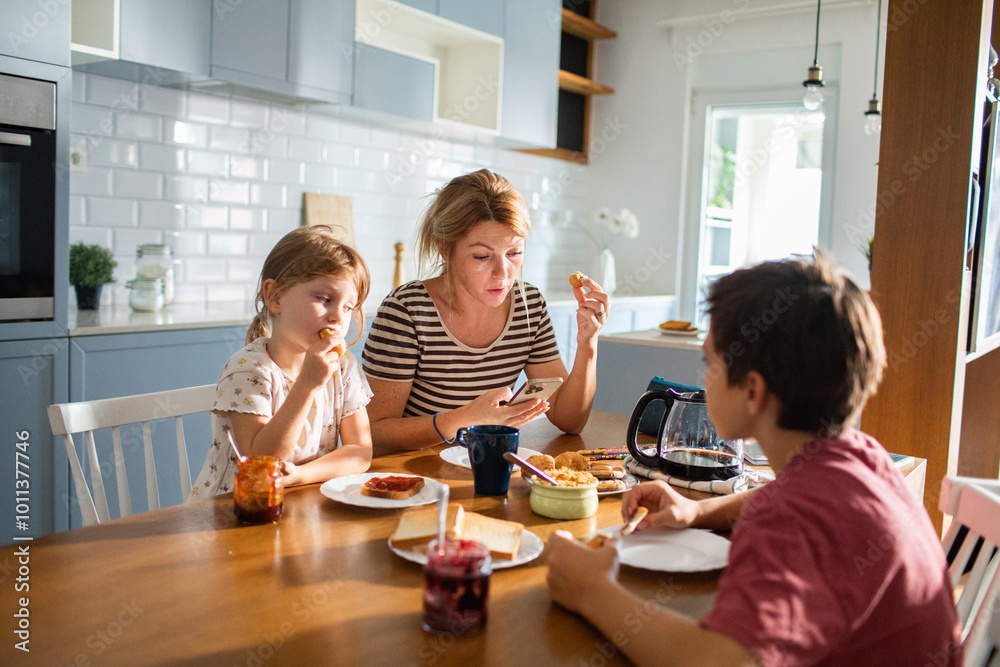 Mother eating breakfast with her kids on kitchen table Mother eating breakfast with her kids on kitchen table