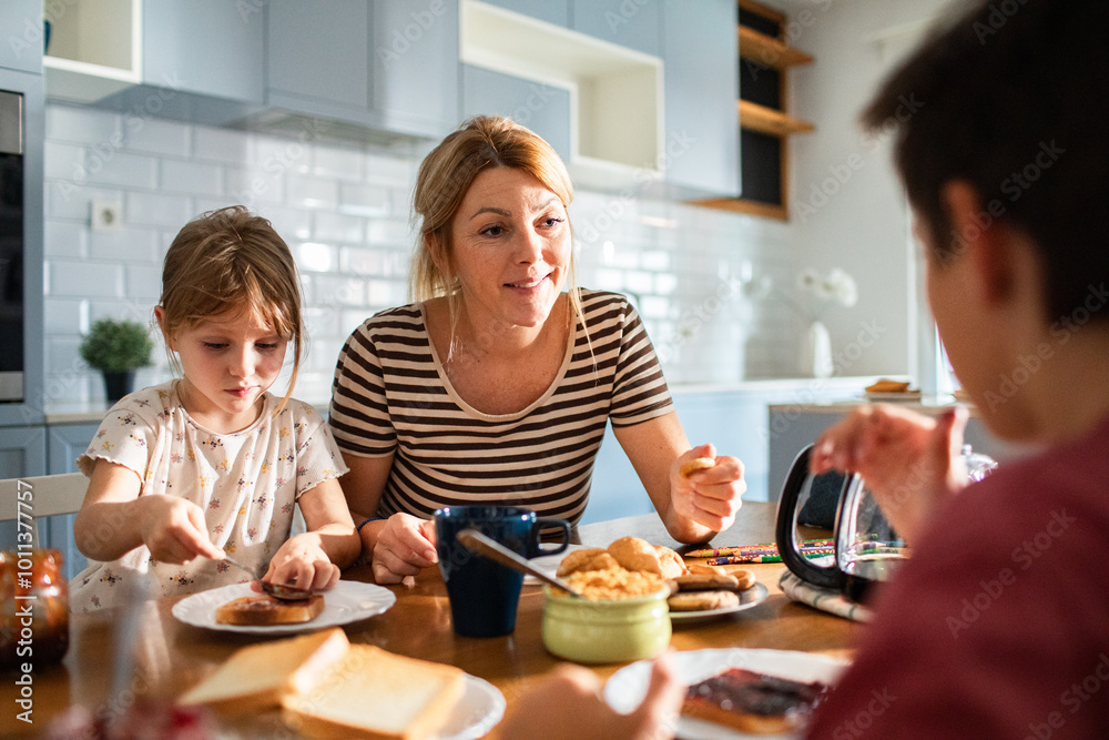 Mother eating breakfast with her kids on kitchen table Mother eating breakfast with her kids on kitchen table