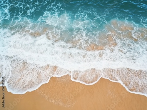 Aerial view of ocean waves lapping onto a sandy shore.