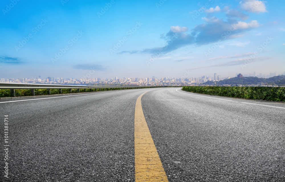 Scenic Winding Road Leading to City Skyline Under Blue Sky Scenic Winding Road Leading to City Skyline Under Blue Sky