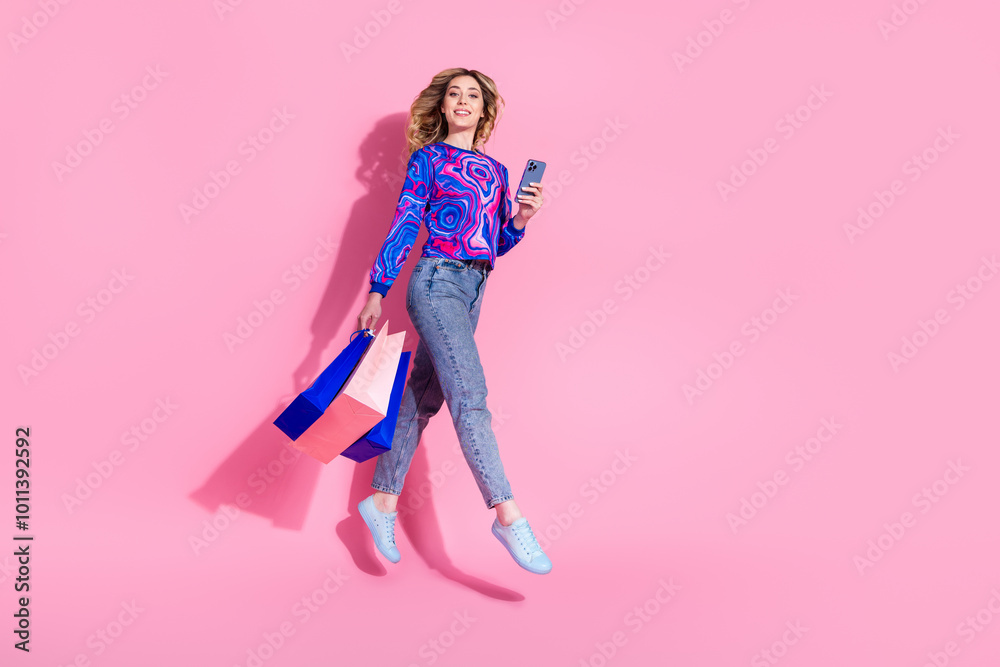 Photo of jumping very happy lady bring packages from shopping mall order taxi using smartphone isolated on pink color background Photo of jumping very happy lady bring packages from shopping mall order taxi using smartphone isolated on pink color background