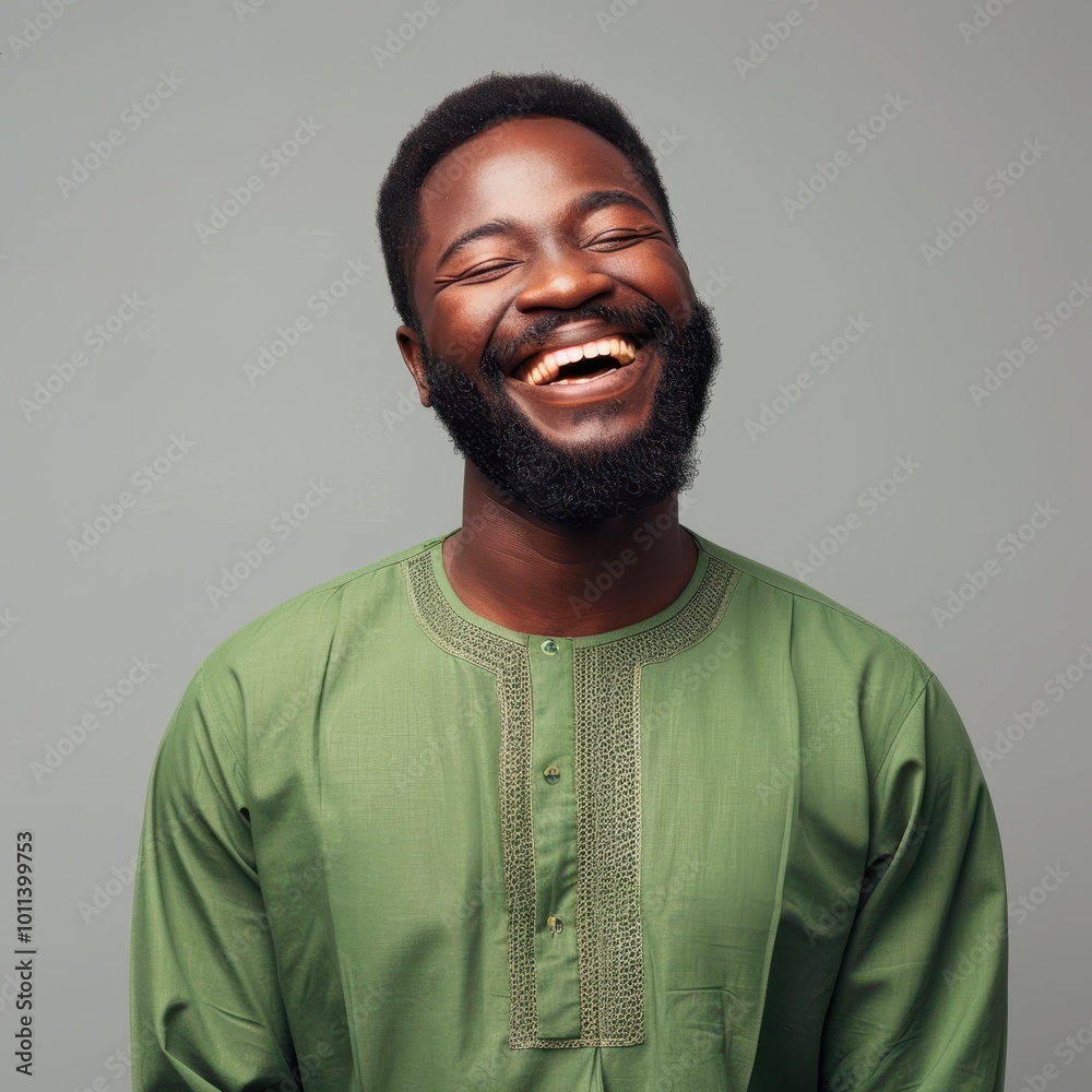 Obraz premium A cheerful Nigerian man in his 40s with short black hair, wearing a green traditional attire, smiling broadly against a neutral background.