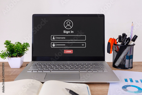 A laptop computer on the desk with a login page on the screen.