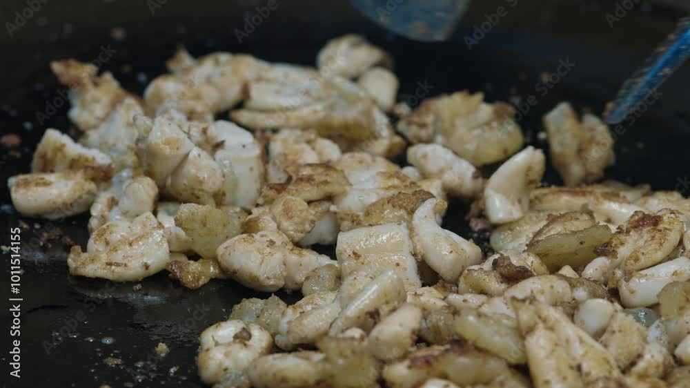 Stir-fried squid eggs at street food stall getting cut and turned by unseen chef with couple of spatulas. Local dish made of seafood in large flat pan with oil for sale at thai night market. Stir-fried squid eggs at street food stall getting cut and turned by unseen chef with couple of spatulas. Local dish made of seafood in large flat pan with oil for sale at thai night market.