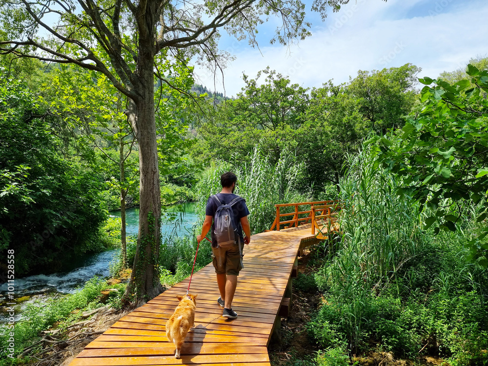 Active man with Pembroke welsh corgi dog walking and enyoing the amazing nature in Krka National Park, Croatia.