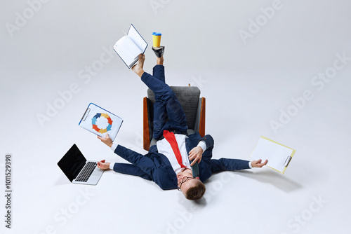 Quadro su tela Businessman lying on ground, his lags in multiple directions, managing papers, laptop, and phone calls
