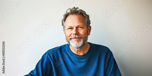 Happy senior man with a beard in a blue sweatshirt smiling against a white background