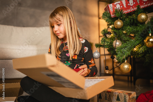 young girl child open Christmas gift with expectation and delight.