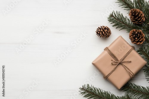 Top view of wrapped gift box with pine cones and branches on white wooden background