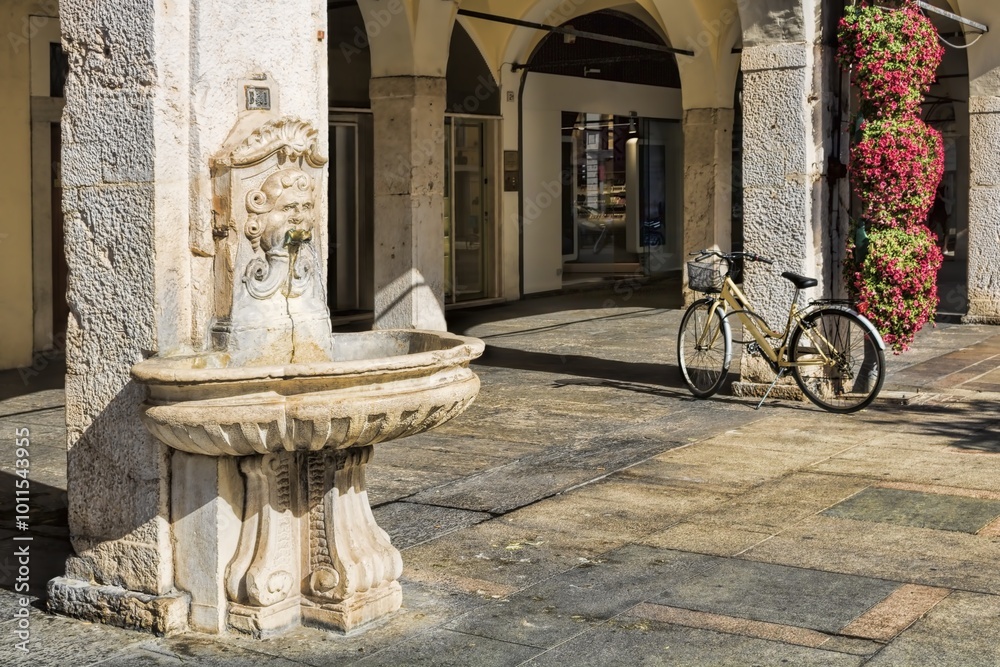 brescia, italien - 09.10.2023 - arkaden mit altem brunnen und fahrrad