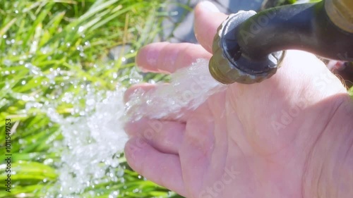 Hand being washed under running water in a garden in slow motion 300fps photo