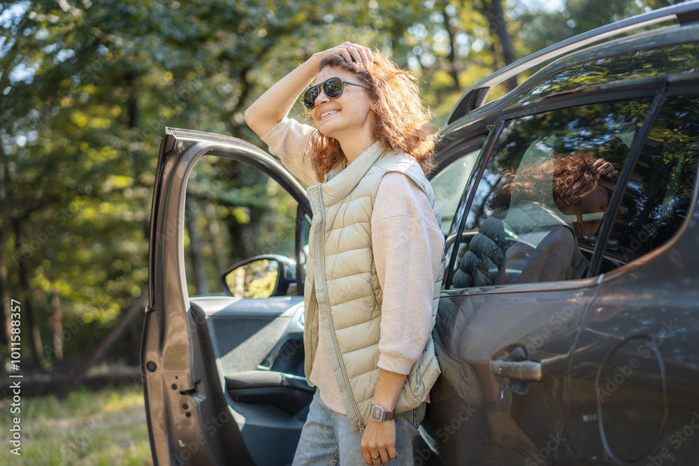 Happy woman driver traveling by car in forest enjoying freedom and nature