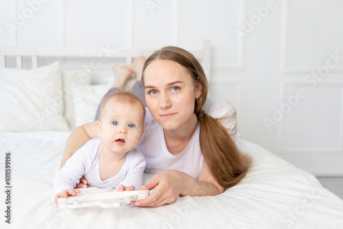 mom plays with baby wooden toy horse on the bed at home, happy family