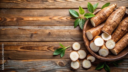 Fresh cassava root with slices and green leaves on a rustic wooden background photo