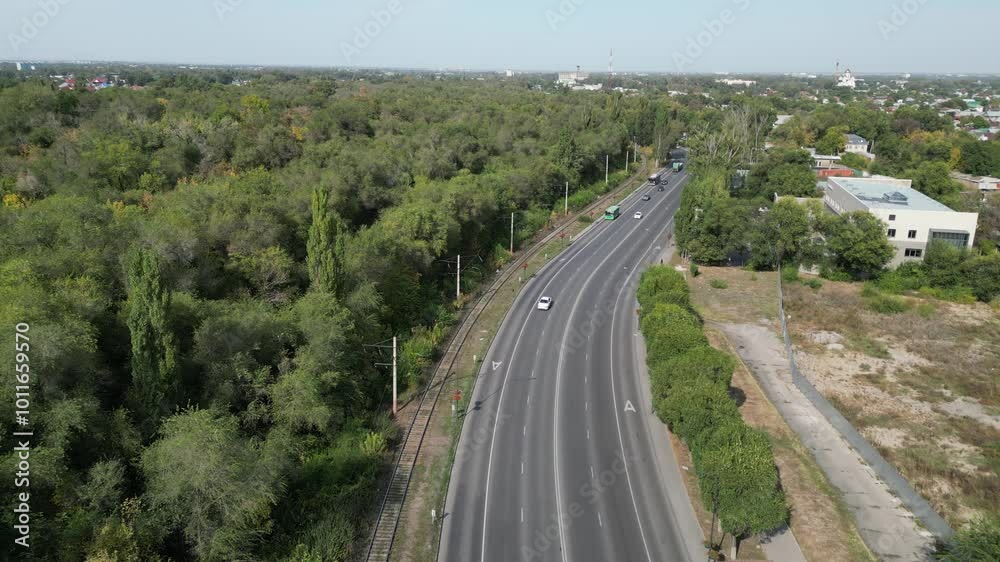 Almaty, Kazakhstan - 10.02.2024 : Traffic on the road located along buildings and groves with trees. Almaty, Kazakhstan - 10.02.2024 : Traffic on the road located along buildings and groves with trees.