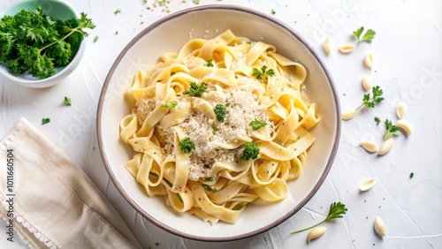 A bowl of fettuccine pasta with parmesan cheese, garlic, and parsley on a white table.