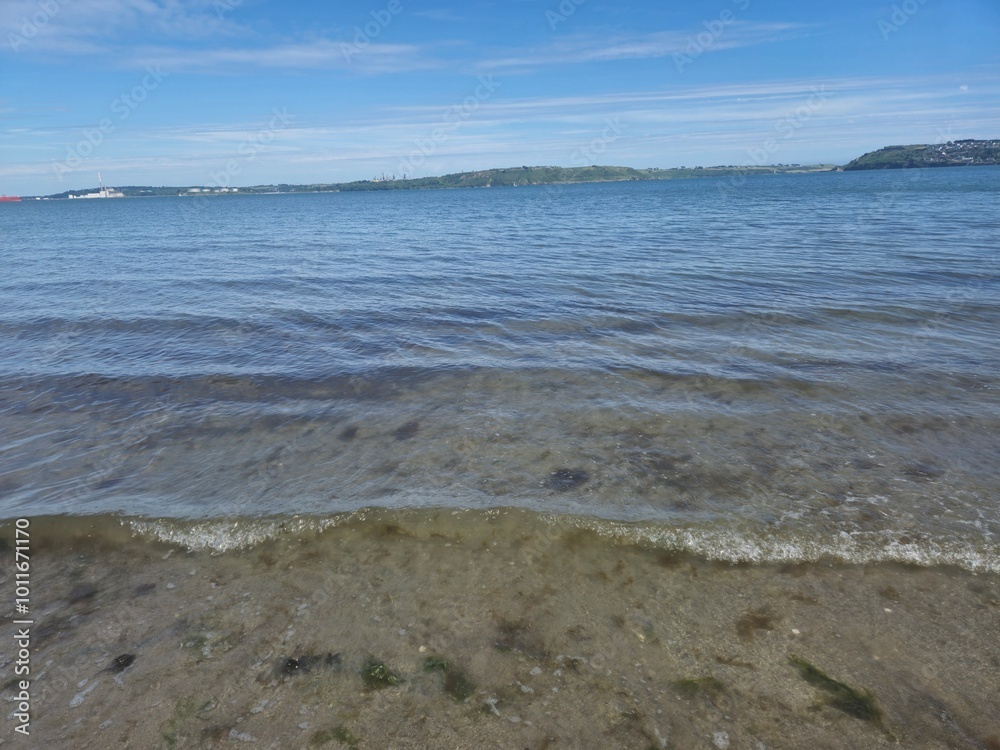 Sunny Summer Beachscape: Waves And Shoreline Under A Blue Sky Sunny Summer Beachscape: Waves And Shoreline Under A Blue Sky