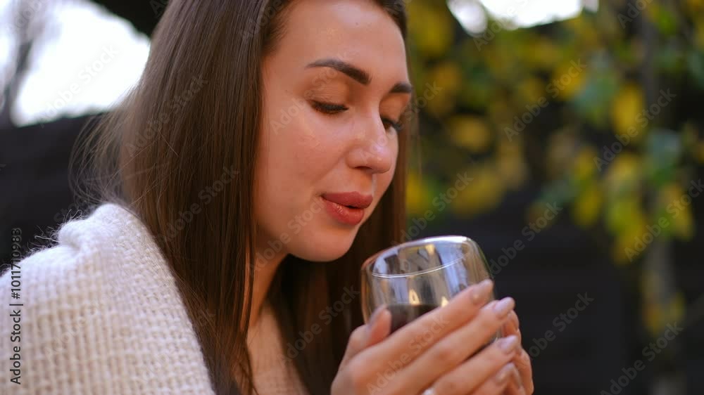 A woman is relishing a peaceful and tranquil moment while savoring a glass of wine in a serene outdoor setting A woman is relishing a peaceful and tranquil moment while savoring a glass of wine in a serene outdoor setting