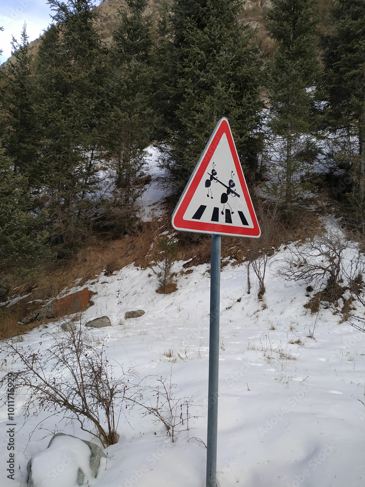 Warning sign alerting travelers to the presence of crossing reindeer in a snowy forest landscape during wintertime Warning sign alerting travelers to the presence of crossing reindeer in a snowy forest landscape during wintertime