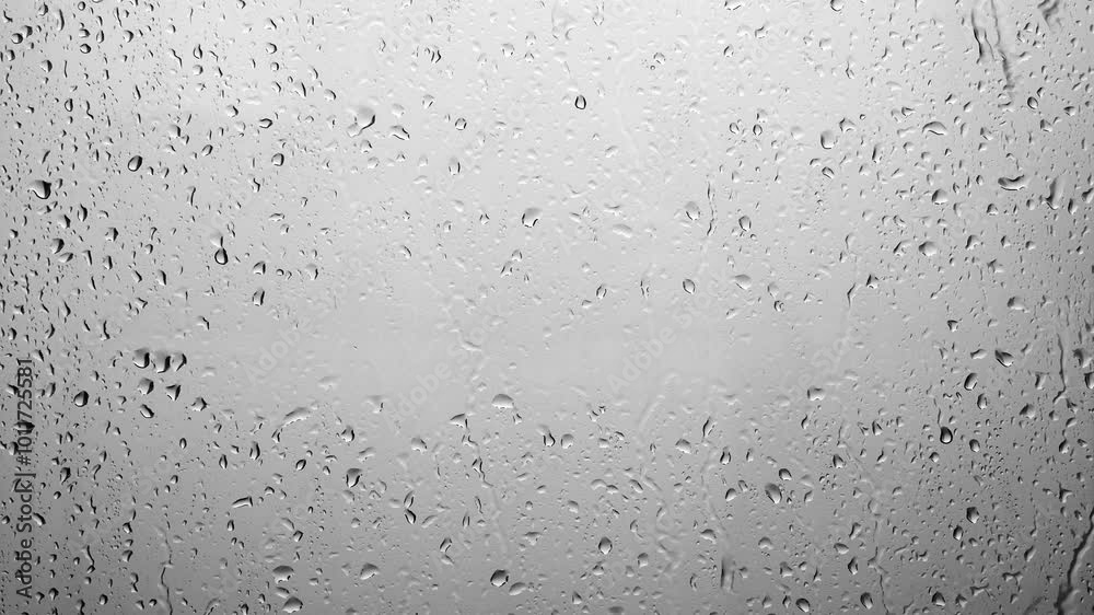 Raindrops falling down the window glass. Abstract background of raindrops in gray tones