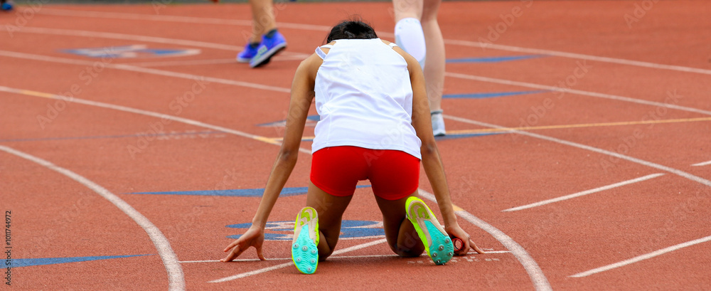 Runner in the on your mark position ready to start a track relay race Runner in the on your mark position ready to start a track relay race
