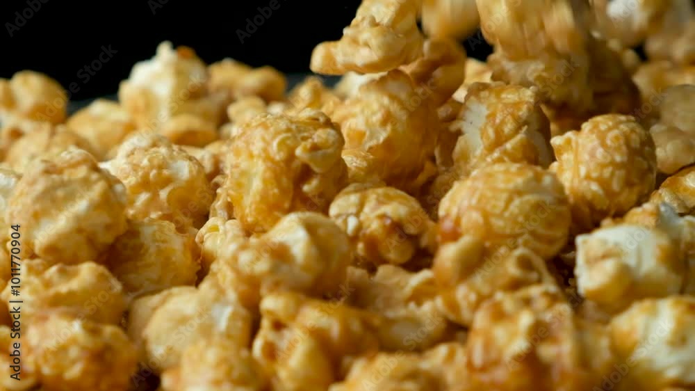 Caramelized sweet popcorn pours and spins, black background, slow motion Caramelized sweet popcorn pours and spins, black background, slow motion
