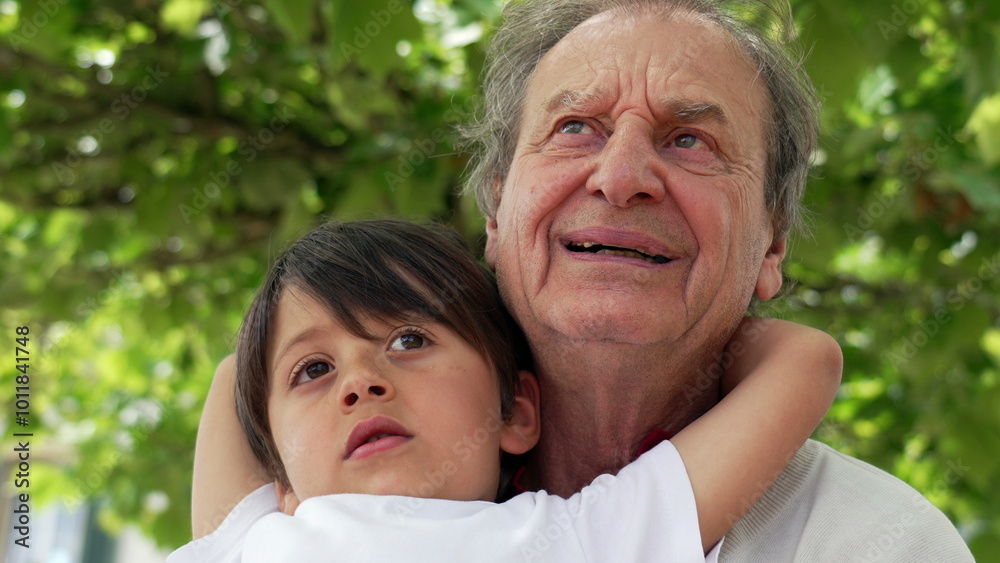 Grandfather and grandson looking upwards while hugging at an outdoor cafe, capturing a thoughtful and loving moment between generations, surrounded by lush green foliage Grandfather and grandson looking upwards while hugging at an outdoor cafe, capturing a thoughtful and loving moment between generations, surrounded by lush green foliage